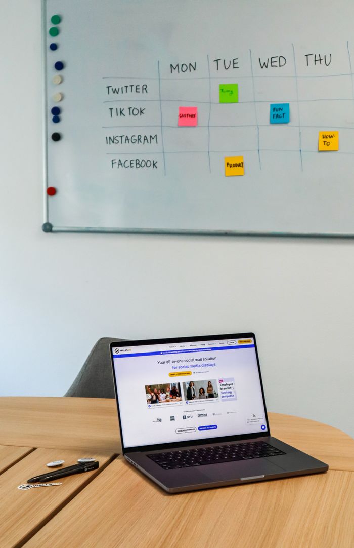 Un espace de travail moderne avec un ordinateur portable et un planning sur tableau blanc dédié aux plateformes de réseaux sociaux.
